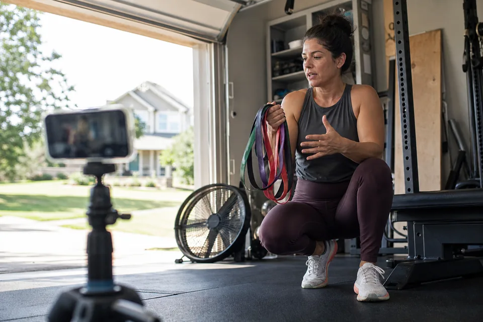 Adult creator filming a hook for a fitness product in a garage gym with a phone on a tripod